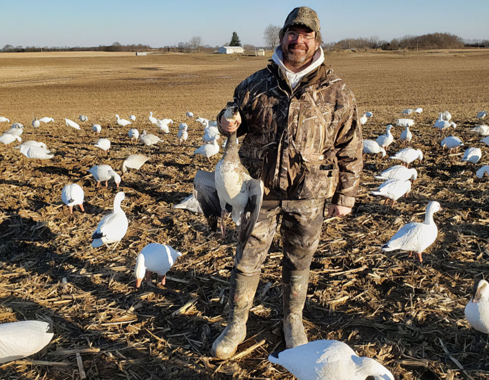 male hunter holding up a snow goose