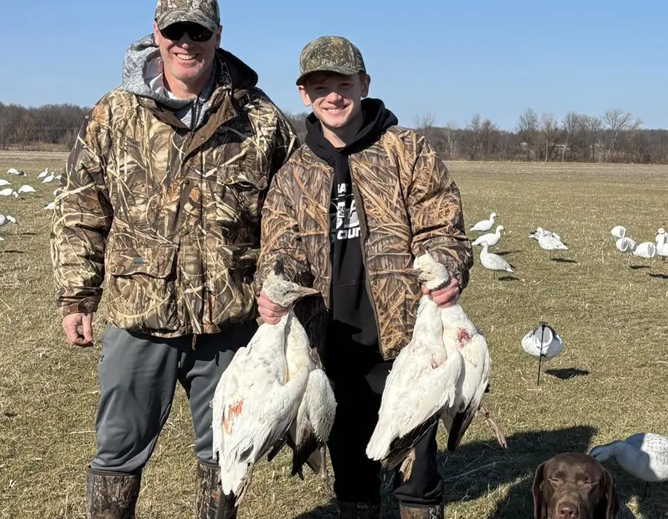 young male hunter holding up a snow geese